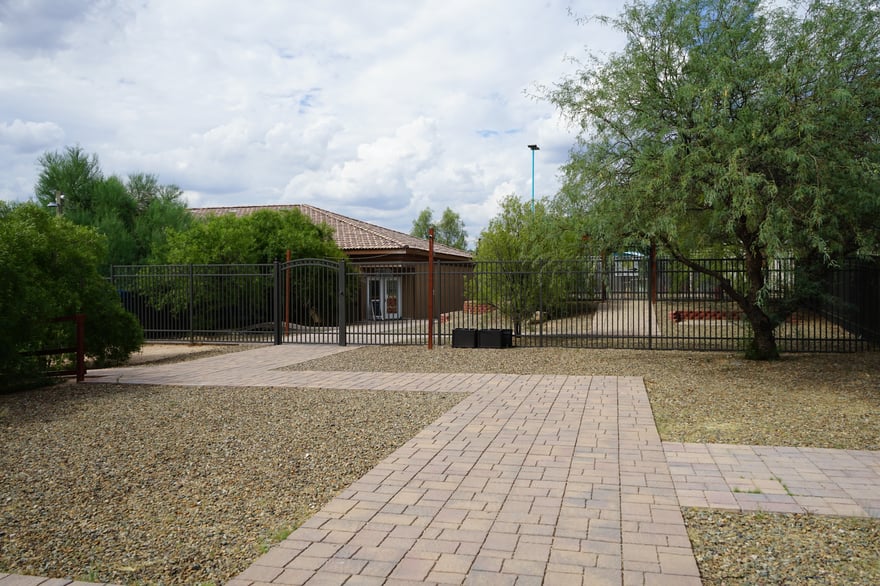 Exterior view of the Cave Creek facility building with a paver courtyard, wrought-iron gate, and desert landscaping.