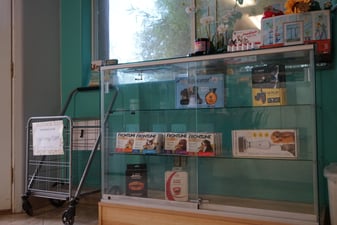 An indoor retail display case at Partners Dogs holding Educator e-collars, part of the conditioning process trainers walk owners through before use.