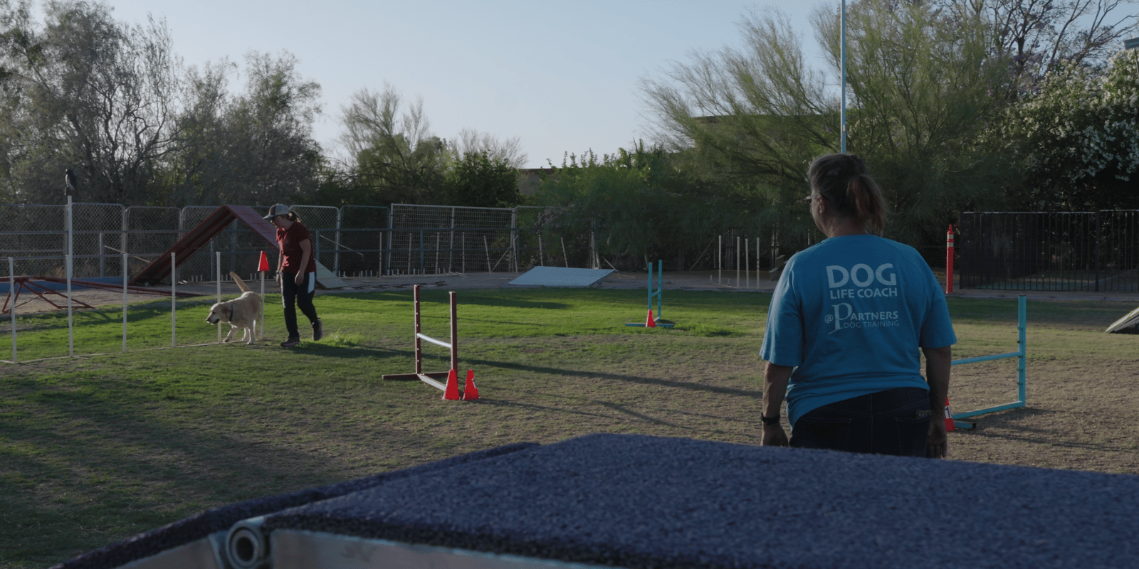 Wide view of the Cave Creek desert agility field with jumps set up and a staff member out on the course.