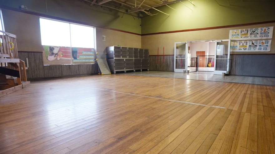 An empty indoor hall at the Scottsdale campus with kennels along one side and a wood floor.