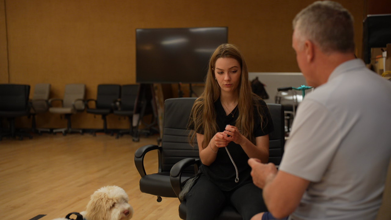 A Partners Dogs trainer coaching a client through holding the leash while her dog settles